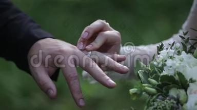 新娘在新郎`手指上戴戒指。 新郎把新娘的结婚戒指戴在手指上。 结婚双手戴戒指